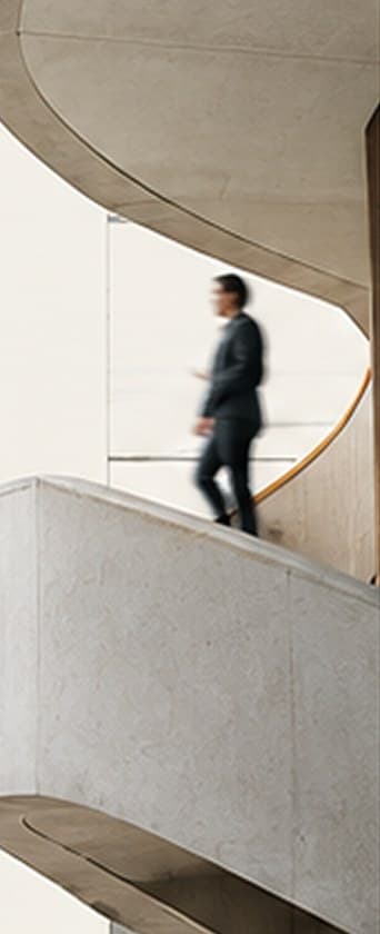 Pessoa descendo uma escada curva de concreto em uma arquitetura clara e ampla